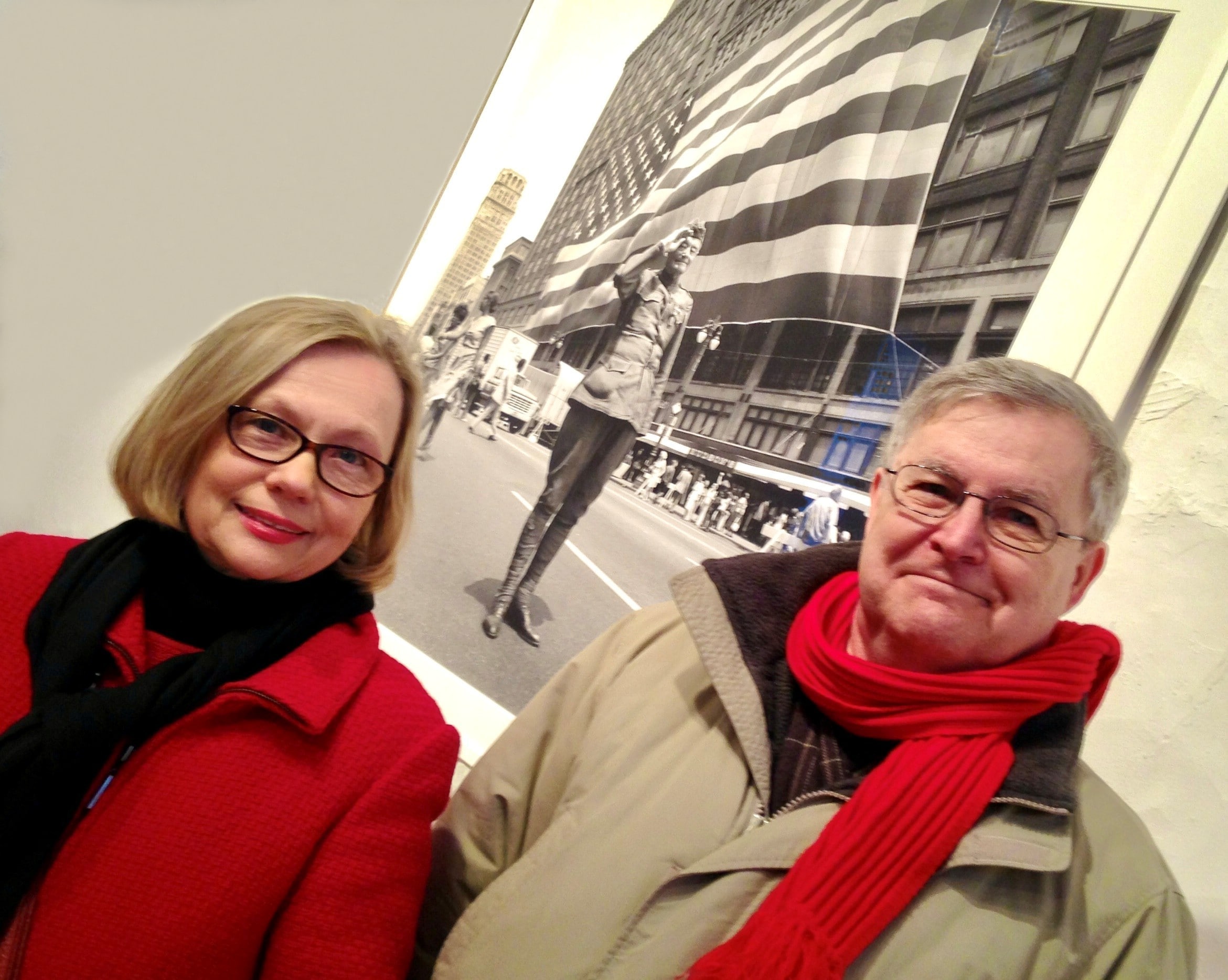 Detroit art gallery visitors stand in front of photo showing the giant flag displayed on the (long-gone) JL Hudson Department Store for special events.